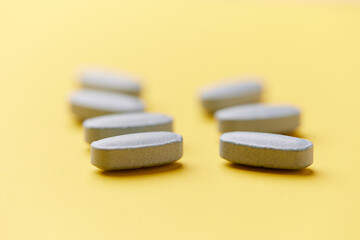 Multivitamin tablets on bright paper background. Close up. Copy space	