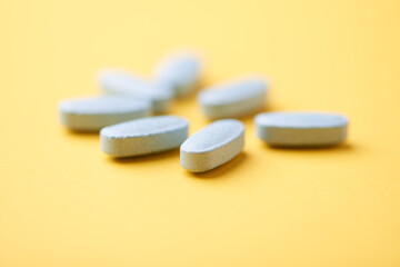 Multivitamin tablets on bright paper background. Close up. Copy space	