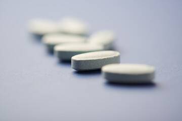 Multivitamin tablets on bright paper background. Close up. Copy space	