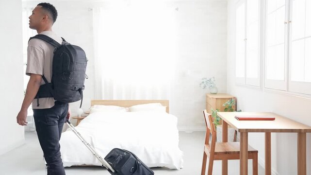 ホテルの部屋にスーツケースを持って立つ黒人男性旅行者