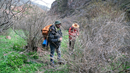 Naklejka premium Two men are walking through the forest through a thicket of dry bushes. Friends are going camping. Trekking, hiking, adventure and tourism