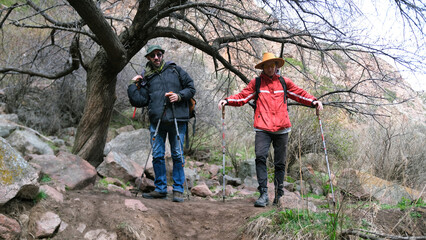 Two friends have chosen a place for a short rest. The guys are standing by a big tree covered with...