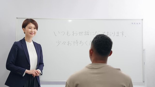 A female teacher teaches business terms to a black man at a Japanese language school