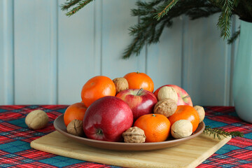 Christmas still life with tangerines, apples and walnuts on a plate