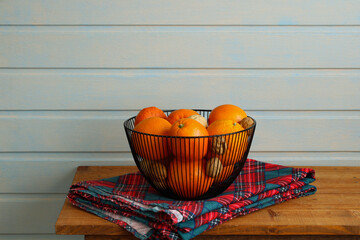 Wire basket overflowing with oranges and walnuts on rustic wooden table