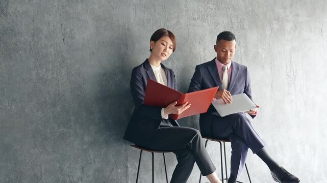 A black male businessman and a Japanese female staff member having a conversation in a stylish room