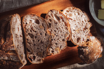 cranberry walnuts sourdough bread sliced placed on wooden cutting board.