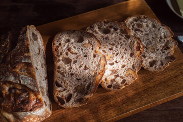 cranberry walnuts sourdough bread sliced placed on wooden cutting board.