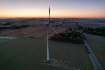 Wind turbine with rotating blades at sunset symbolizing green renewable energy and European Green...