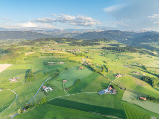 Aerial view of rural landscape in Swiss canton of Fribourg. Hills and forests in evening sunlight in district of Sense.