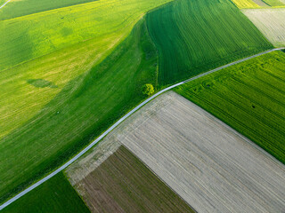 Aerial view of rural road through countryside meadows and farmland in Canton of Fribourg in Switzerland. 