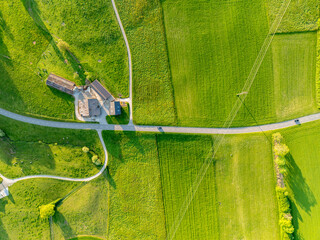 Aerial view of rural road through countryside meadows and farmland in Canton of Fribourg in Switzerland. 