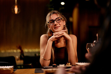 Young Woman Smiling at Restaurant Dining Table in Cozy Ambiance