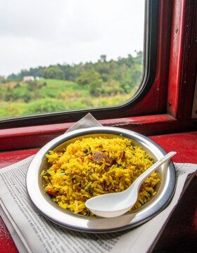 Candid travel photo of Indian Poha, a savory flattened rice breakfast, served on a train. Authentic and delicious street food experience while traveling