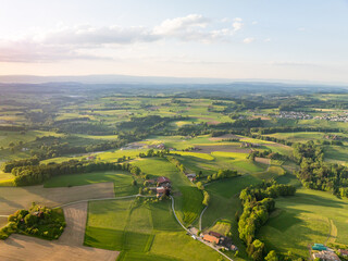 Aerial view of rural landscape in Swiss canton of Fribourg. Hills and forests in evening sunlight in district of Sense.