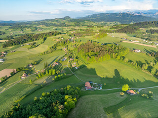 Aerial view of rural landscape in Swiss canton of Fribourg. Hills and forests in evening sunlight in district of Sense.