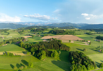 Aerial view of rural landscape in Swiss canton of Fribourg. Hills and forests in evening sunlight in district of Sense.
