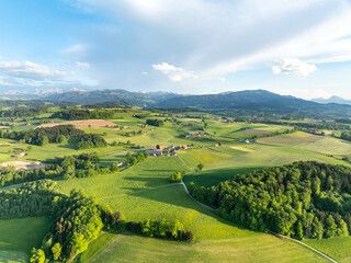 Aerial view of rural landscape in Swiss canton of Fribourg. Hills and forests in evening sunlight in district of Sense.
