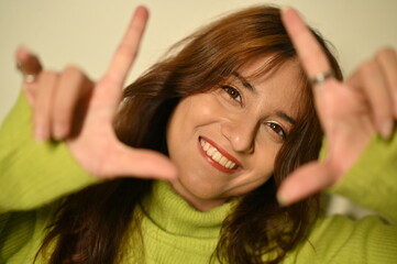 beautiful young woman with hands up. fingers posing.  making click by fingers in camera. smile emotions. joyfull creative. positive play mood