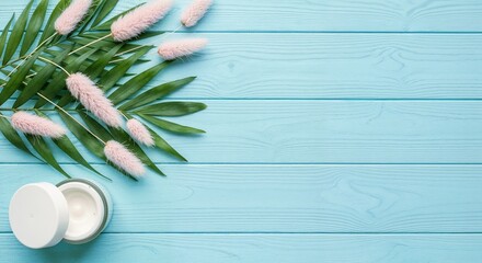 Top-Down Flat Lay of Skincare Jar with Palm Leaves and Pink Flowers on Pastel Pink Wooden Background
