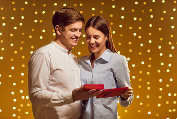 Husband and wife celebrate Valentine Day or anniversary at home, opening a gift box while...