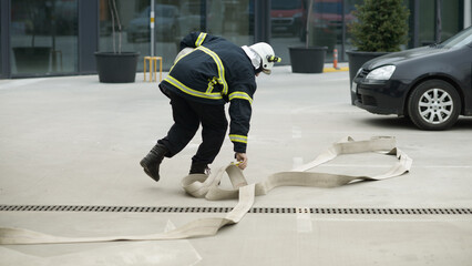 A firefighter in full protective gear unrolls a fire hose during an emergency response in Ruse,...