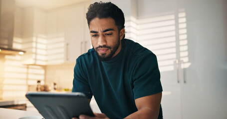 Tablet, reading and man in kitchen in morning with networking, communication or mobile app in home. Digital technology, research and male person thinking for texting, contact or social media in house