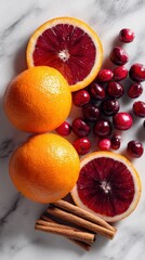 Vibrant blood oranges and bright cranberries are arranged with cinnamon sticks on marble surface