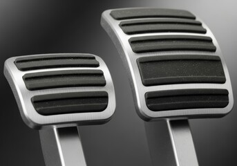 A close-up of two modern car pedals, the brake and gas, with brushed silver metal and textured black rubber grips. The clean, sleek design and clear distinction between the two pedals highlight safety