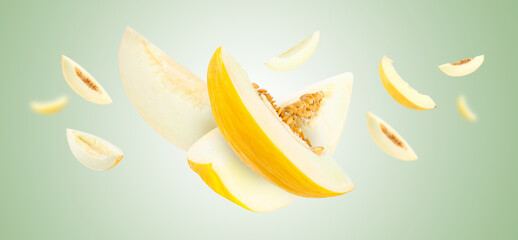 Cut fresh ripe melons swirling in air against light green gradient background
