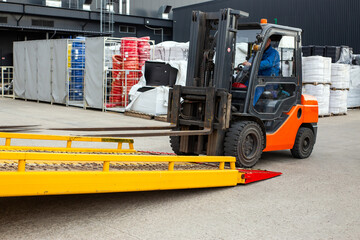 A forklift is driving a yellow trailer with a red and white sign on it