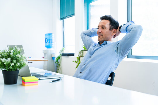 Businessman relaxing at desk in modern office after work