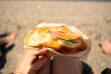 Appetizing half-consumed croissant filled with salmon and salad leaves, captured in natural light -...