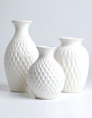 Three white ceramic vases with a textured diamond pattern