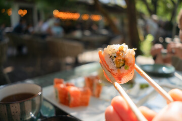 Fresh salmon and cucumber sushi roll held with chopsticks, beautifully presented with authentic...