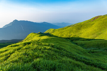 Sunlit Green Meadows with Distant Mountain Peaks