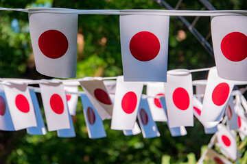 Banners adorned with vivid red circles sway gently among lush greenery during a lively gathering
