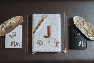 Flat lay of wedding accessories with bride and groom notebooks, jewelry, golden pen and decorative...