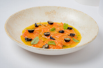 Exquisite dish combining fresh salmon slices with citrus flavors, black olives, and fragrant herbs