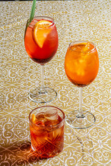 Three delicious cocktails sit on a beautifully patterned tablecloth, inviting summer enjoyment