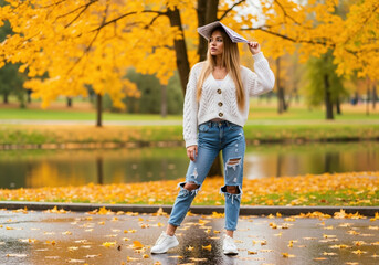 Woman in white cable knit cardigan and ripped jeans holding book over head in autumn park. Student lifestyle and educational fashion for back to school and college campaigns