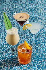 Five beautiful drinks are arranged on an ornate tablecloth, adding to the festive vibe
