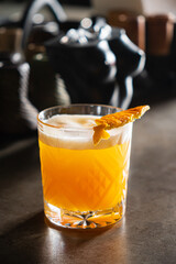 A vibrant orange cocktail on the bar, crowned with a citrus garnish