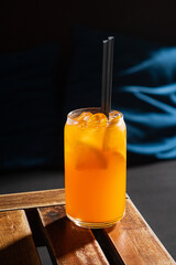 Bright orange drink with ice and straws on a wood table, perfect for warm days and relaxing