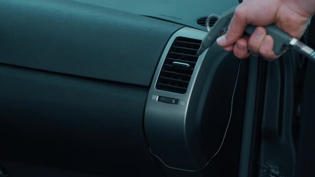 A skilled hand uses a professional tool to clean car air vents for better airflow, efficiency, and hygiene