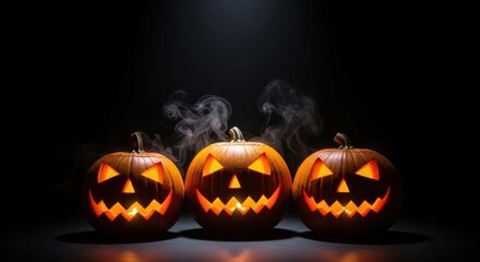 Three spooky carved halloween jack o lanterns glowing with orange light on a dark background