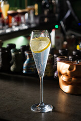 A crisp drink brightens a cheerful evening, glowing in low bar lighting with colorful bottles