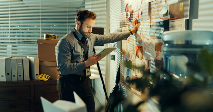 Man, detective and tablet at board in office for investigation, evidence or documents with reading for criminal case. Investigator, tech and problem solving with crime analysis or info at night