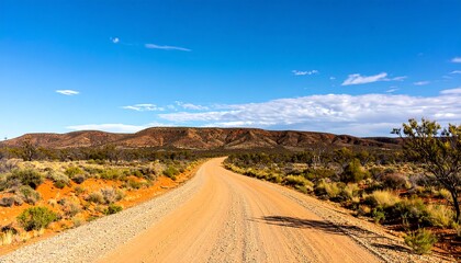 Fototapeta premium Dusty road stretching into a vast landscape under a vibrant sky