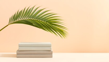 Stack of beige books with green palm frond on peach background image photo